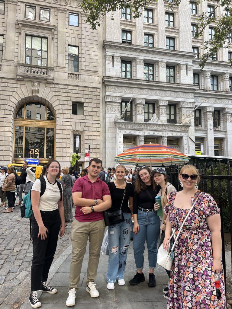 Group of students from different cultures and countries standing with their advisor on Wall Street