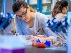 Photo of student writing observations while performing experiment.