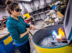 Photo of student using blowtorch to melt copper for sculpture.