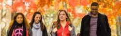 Students walk across campus with fall foliage in the background.