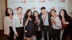 Seven students smile and gesture at the camera.