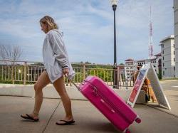 A student pulls a large hot-pink suitcase.