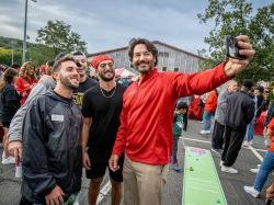 总统 Koppell holds a camera at arm's length to take a "selfie" with students.