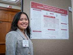 A student stands in front of her research poster.