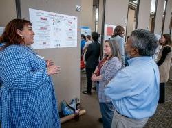 A student speaks as two people view her poster.