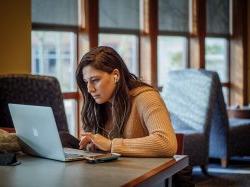 Woman working on a laptop wearing headphones