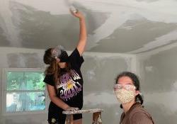 马里亚纳Luna-马丁内斯 paints a ceiling while standing on a ladder.