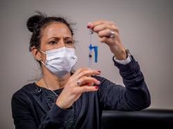 RN to BSN student in protective face mask filling a syringe.