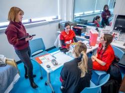 School of Nursing professor talking with students in the Simulation Center.