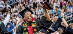 student in cap and gown waving during commencement